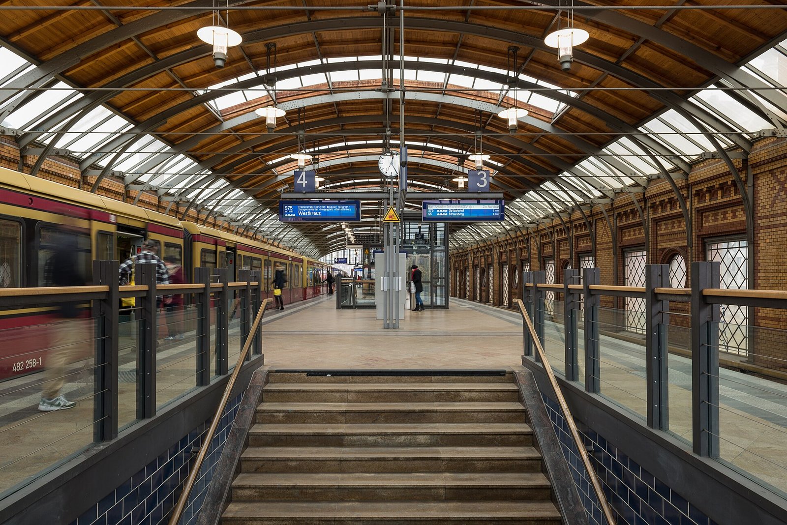 Die Bahnsteighalle der S-Bahn-Station Hackescher Markt mit gewölbtem Holzdach, Backsteinwand und einer einfahrenden S-Bahn