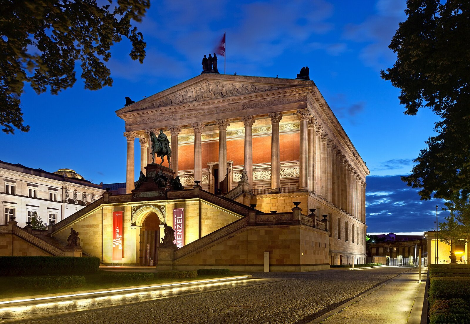 Die Alte Nationalgalerie mit Tempelfront und Freitreppe, abends beleuchtet unter blauem Himmel
