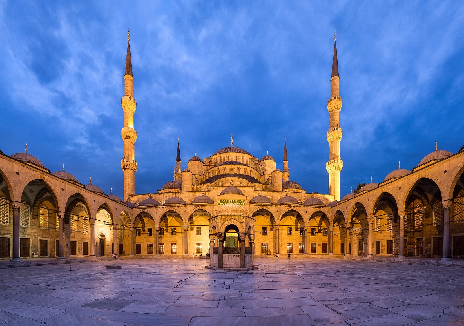 Der Innenhof der Blauen Moschee im Abendlicht mit zwei beleuchteten Minaretten
